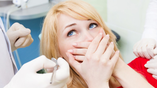 Anxious woman covering her mouth with hands during a dental appointment in Atlanta