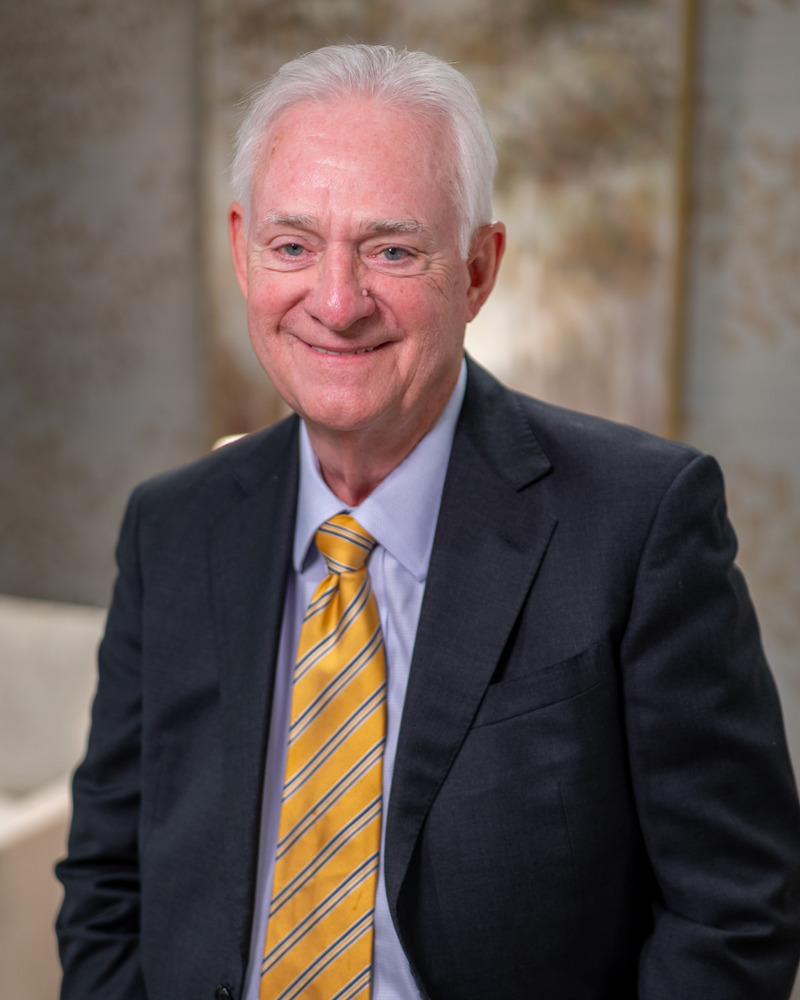 Dr. Thomas Kauffman, experienced dentist, smiling in dark suit and gold tie
