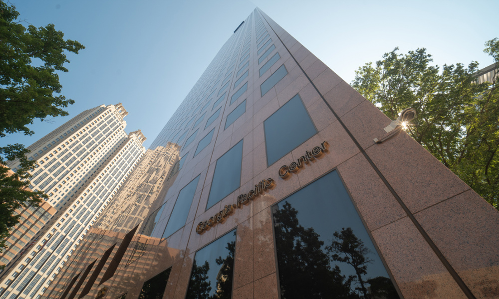 Exterior upward view of Georgia-Pacific Center skyscraper in downtown Atlanta with surrounding trees and blue sky