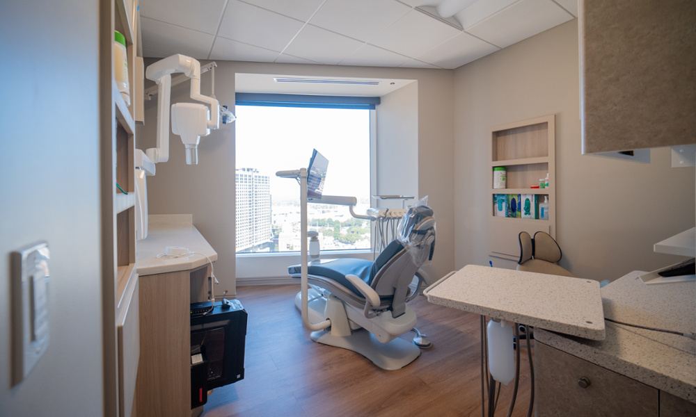 Modern dental exam room with patient chair, X-ray equipment, and panoramic city view window