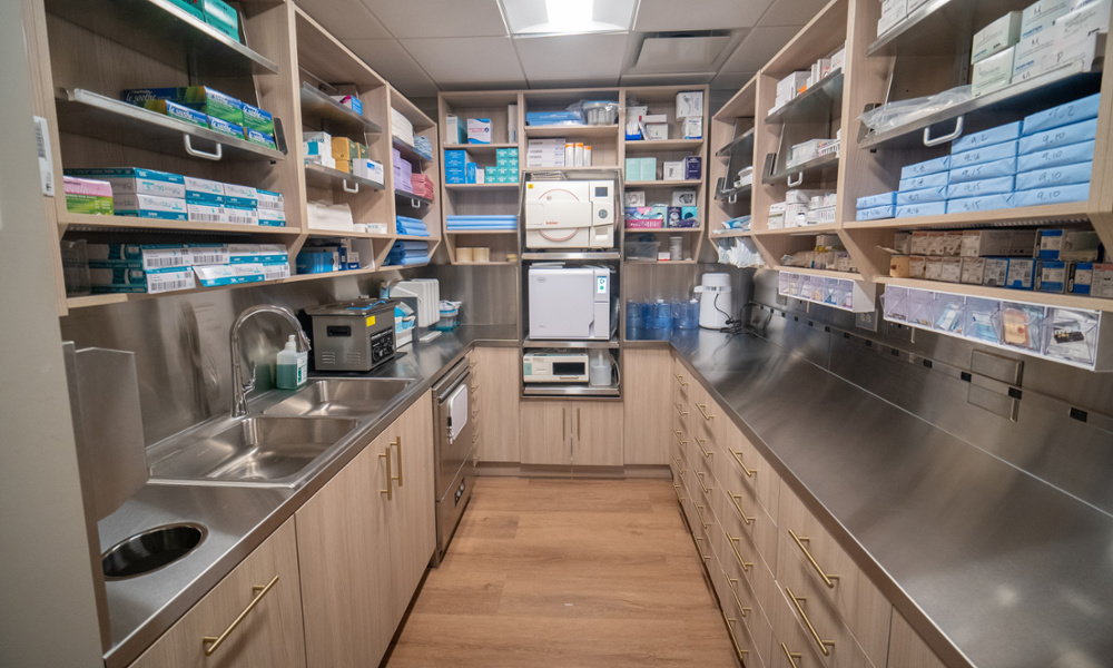 Dental sterilization room with autoclave, stainless steel counters, sink, and fully stocked supply shelves
