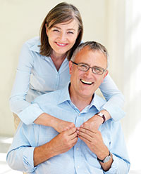 a man and woman hug each other, happy with their dentures