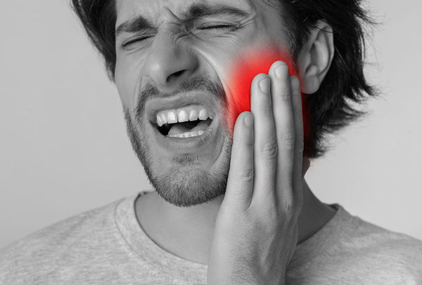 man holding his mouth and wincing in pain