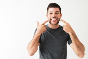 a man points to his smile that was improved through dental bonding
